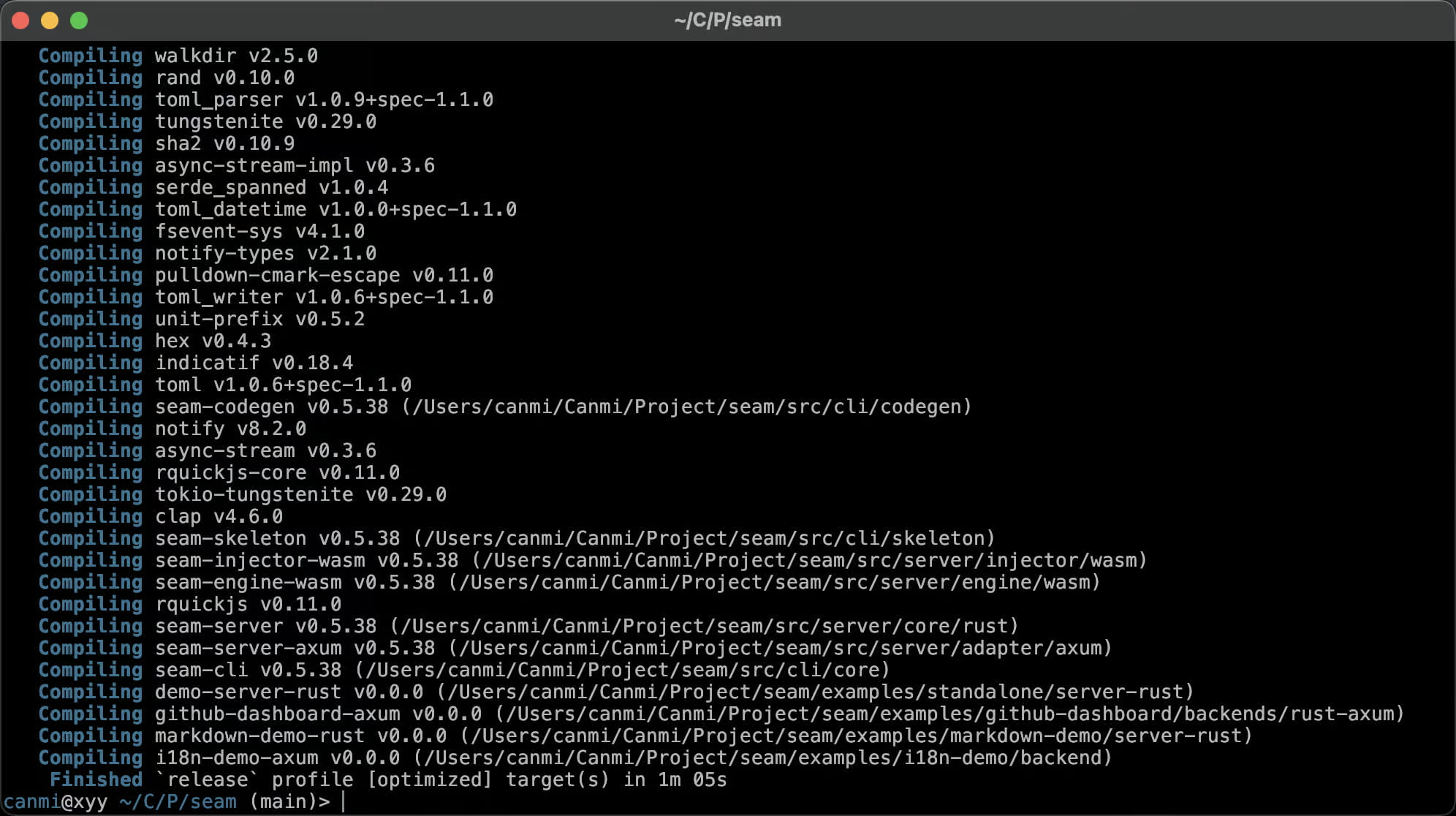 一张深色 macOS 终端窗口的截图，标题为 `~/C/P/seam`，画面中是一次 Cargo release 构建的收尾部分：约四十行青色的 "Compiling" 记录，列出了带版本号的第三方 crate —— walkdir v2.5.0、rand v0.10.0、tungstenite v0.29.0、sha2 v0.10.9、clap v4.6.0、rquickjs v0.11.0、notify v8.2.0、indicatif v0.18.4 —— 随后是项目自身的 workspace 成员，版本均为 v0.5.38，各自标注了路径：位于 `/Users/canmi/Canmi/Project/seam/src/` 下的 seam-codegen、seam-skeleton、seam-injector-wasm、seam-engine-wasm、seam-server、seam-server-axum 和 seam-cli，接着是四个 v0.0.0 的示例 crate（demo-server-rust、github-dashboard-axum、markdown-demo-rust、i18n-demo-axum）。最后一行显示 `Finished \`release\` profile [optimized] target(s) in 1m 05s`，下方是等待输入的 shell 提示符 `canmi@xyy ~/C/P/seam (main)>`。它记录了整个 seam workspace —— 库、server adapter、CLI 以及全部随附示例 —— 在 main 分支上一次干净、无警告的 release 构建，耗时刚过一分钟。